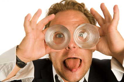 Every office has a goof ball like this. Businessman holding two drinking glasses over his eyes like goggles and sticking his tongue out at you.